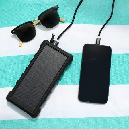 SunSaver 24K solar power bank charging a phone on a towel
