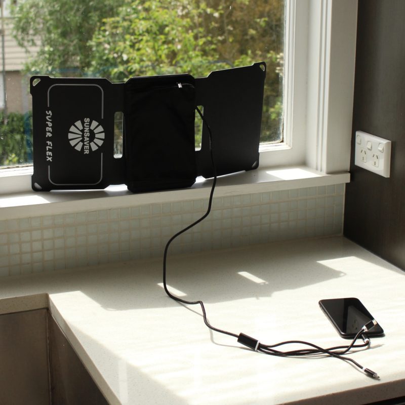 SunSaver Super-Flex portable solar charger charging a phone through a window