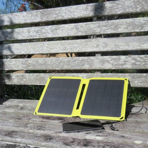 SunSaver Power-Boost charging a smartphone from the sun on a bench